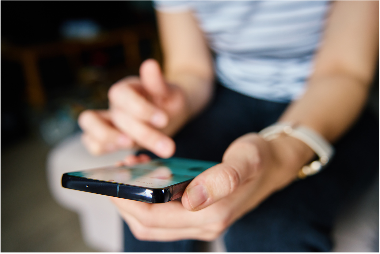 Close-up of a child using a smartphone at home, scrolling with one hand and holding the phone with the other.
