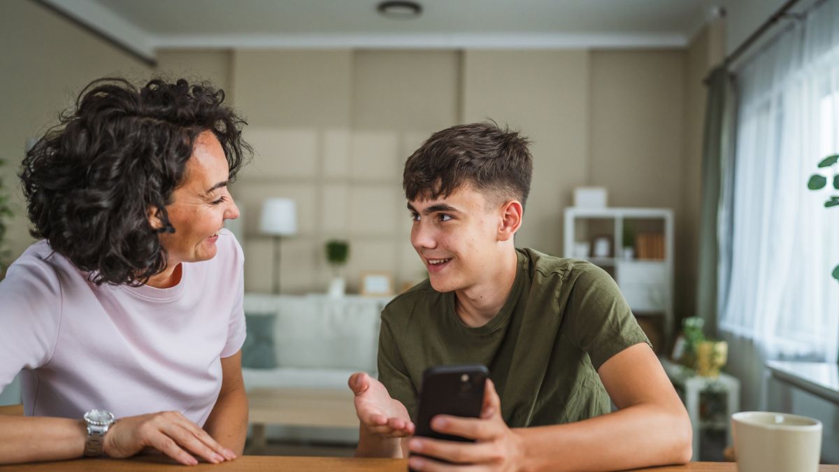 Parent and teenager sitting together discussing smartphone use